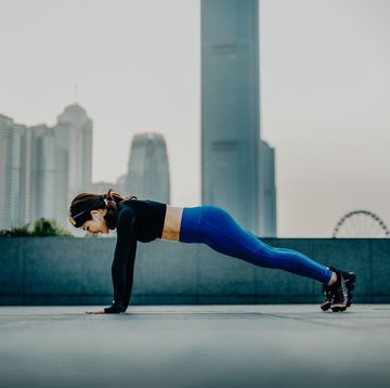 confidence and energetic young asian sports woman exercising and working out outdoors in urban park against city skyline at sunset