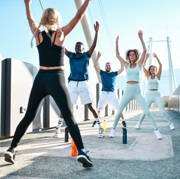 jumping jacks by female fitness instructor while working with multiethnic group outside