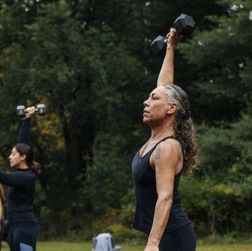 mature woman working out with dumbbells during outdoor fitness class
