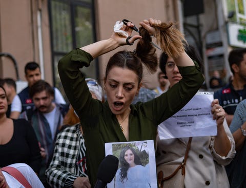 TURKEY-IRAN-WOMEN-RIGHTS-DEMO a woman talking while cutting her ponytail