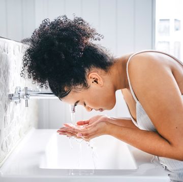 woman washing her face in her bathroom skin