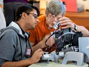 Repair Cafe veteran Joe Margevicius and apprentice Gaurav Aggarwal examine a broken piece of electronics.
