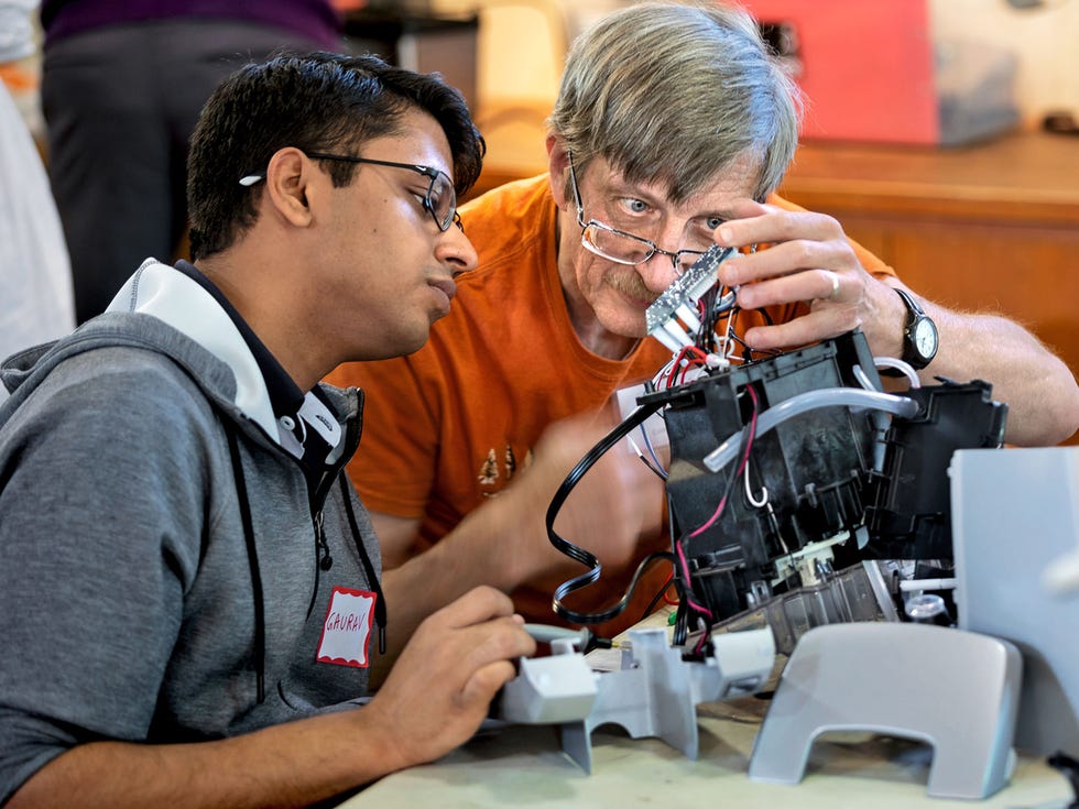 Repair Cafe veteran Joe Margevicius and apprentice Gaurav Aggarwal examine a broken piece of electronics.
