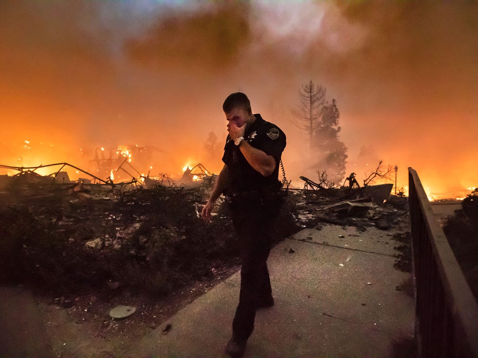 San Rafael Police Officer Mark Wilkinson wipes smoke from his eyes as the Santa Rosa Hilton hotel burns behind him on the evening of last Oct. 9.