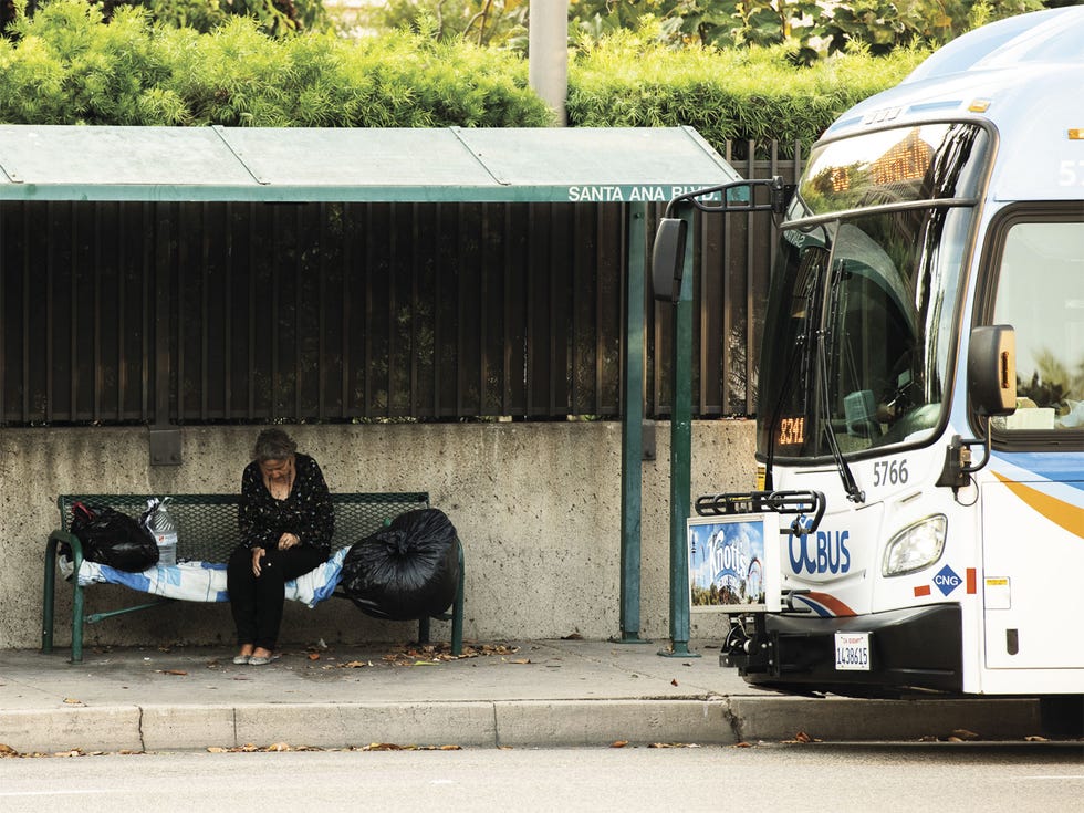 Like most of California, Orange County is seeing an increase in homeless people, like this woman camped out at a bus stop.