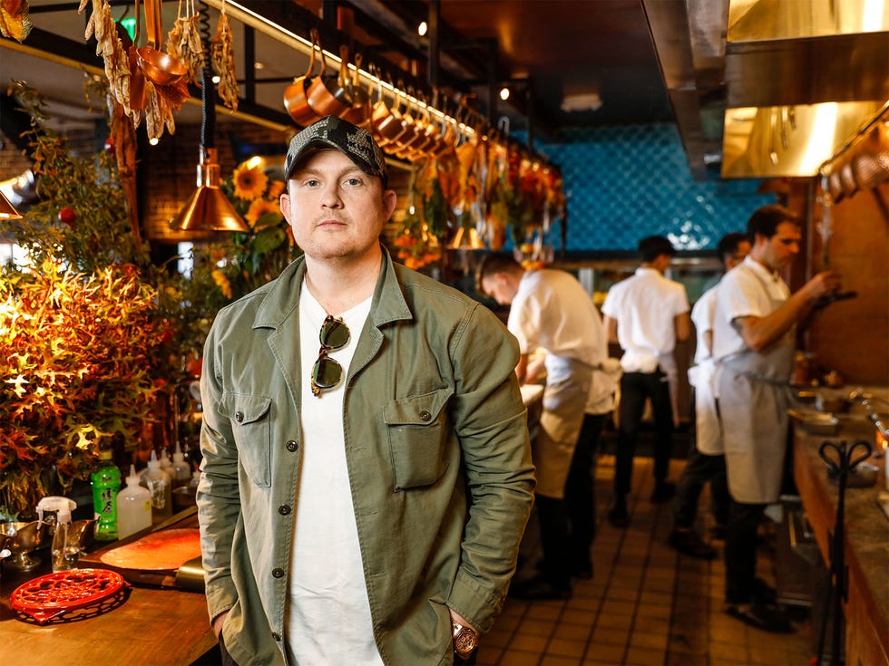 Chef Joshua Skenes in the open Angler kitchen between the counter filled with flowers and herbs used in his recipes and the 32-foot-long open hearth where the restaurant does its live-fire cooking.