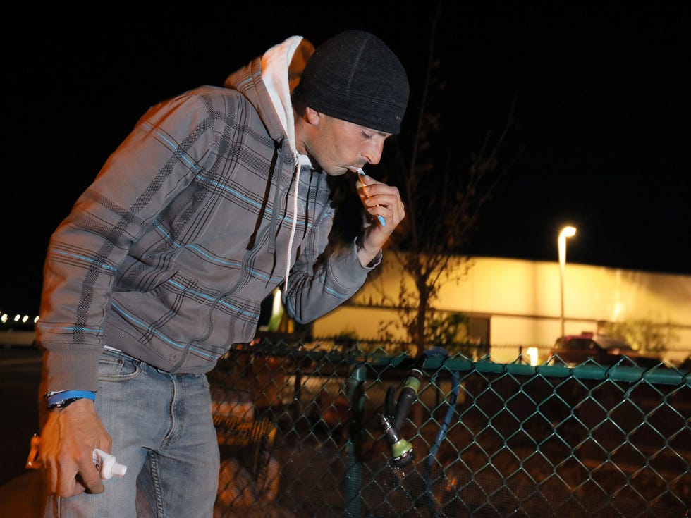 Cliff Johnson, 35, brushes his teeth at a hose made available to the people spending nights here in their cars. He's been unable to work construction jobs due to health problems.
