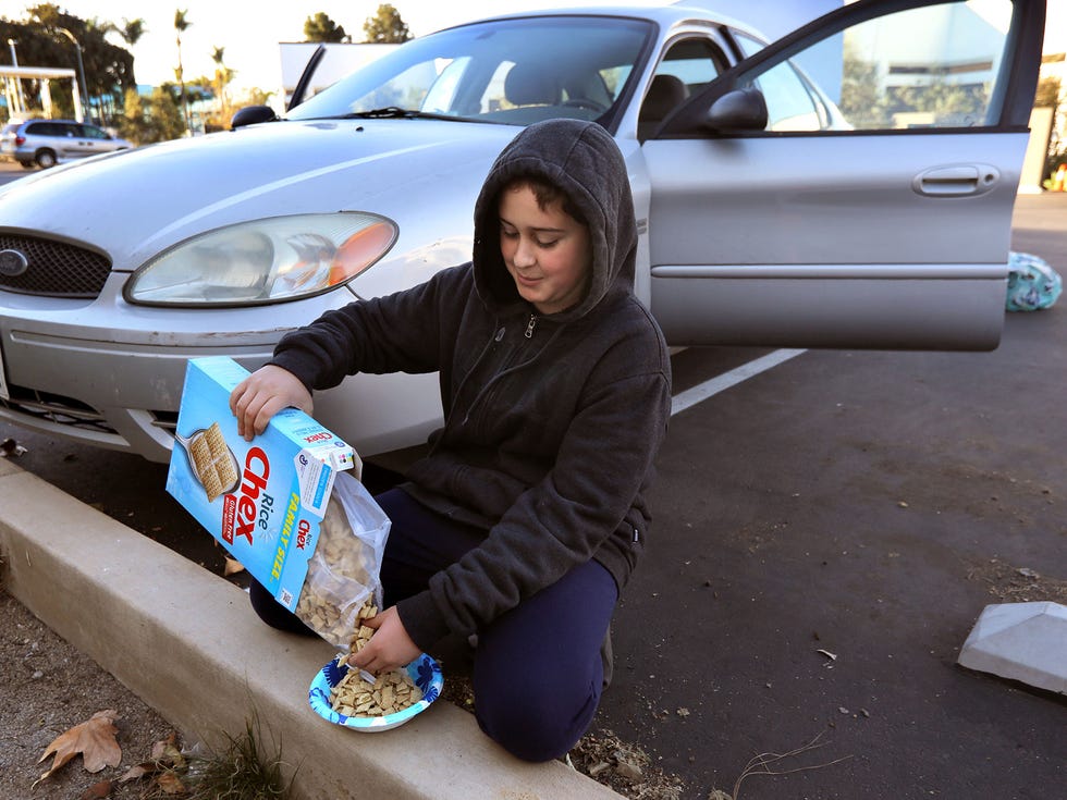 Amram Lender pours a bowl of cereal after he and his mom slept in their Ford Taurus. The 8th grader will soon he's off to school for the day.