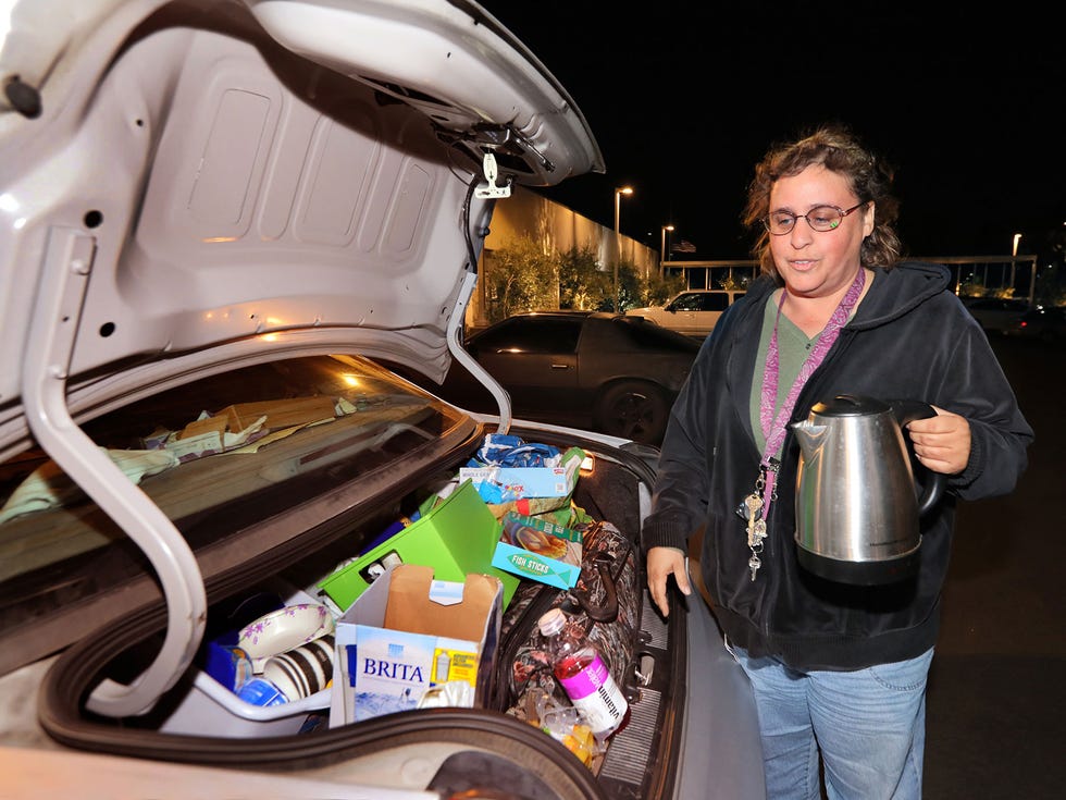 Homeless Naomi Lender gets her coffee pot from her car's packed trunk to get it ready to make tea for the next morning.