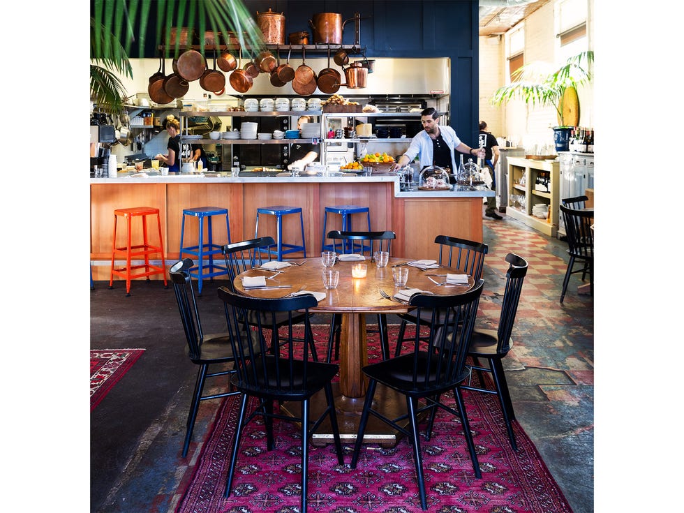 Located in a former Bank of Italy building, the dining room includes exposed brick walls and Oriental rugs partly covering a floor of hardened black tar and old linoleum.
