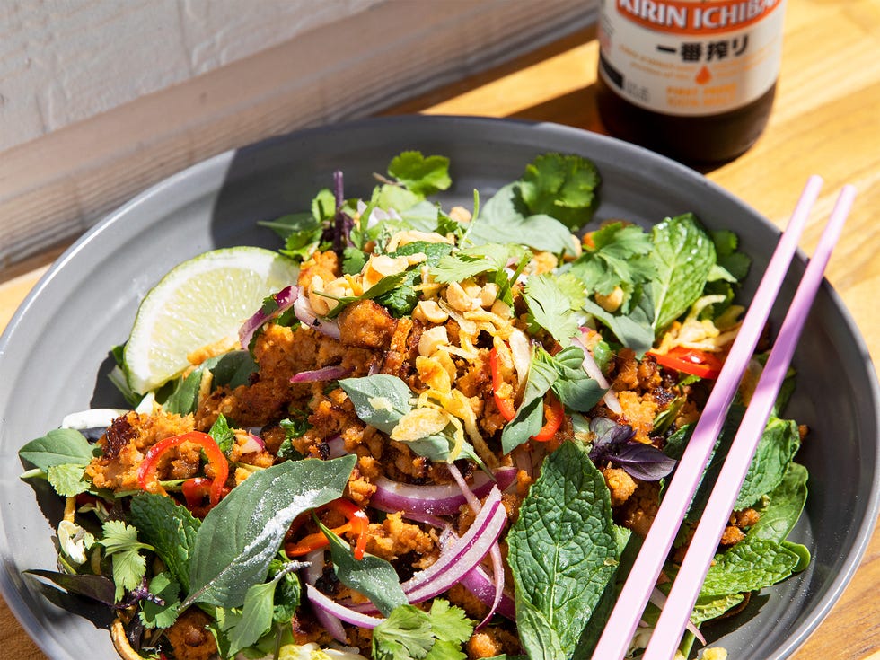 The pork larb noodle bowl, made with minced pork, vermicelli, mixed lettuce, peanuts, chiles, and fried shallots, sits ready to be washed down with a cold beer.