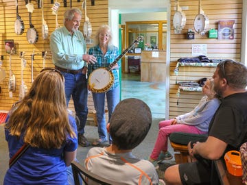 In the display room of the Deering Banjo Company Greg and Janet Deering speak with a family from Tucson, Arizona that are about to take a tour of the facility. The banjo Janet is holding is an Ivanhoe Gold model. At left are the company's Goodtime line of banjos.