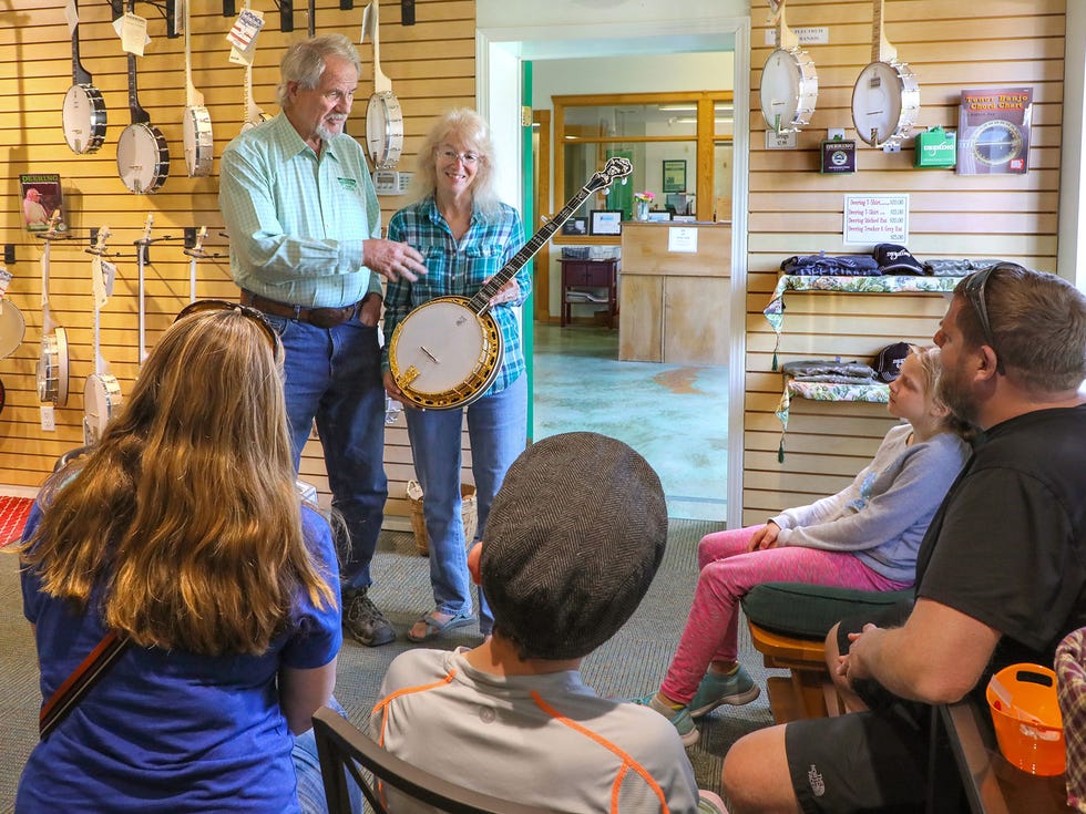 In the display room of the Deering Banjo Company Greg and Janet Deering speak with a family from Tucson, Arizona that are about to take a tour of the facility. The banjo Janet is holding is an Ivanhoe Gold model. At left are the company's Goodtime line of banjos.