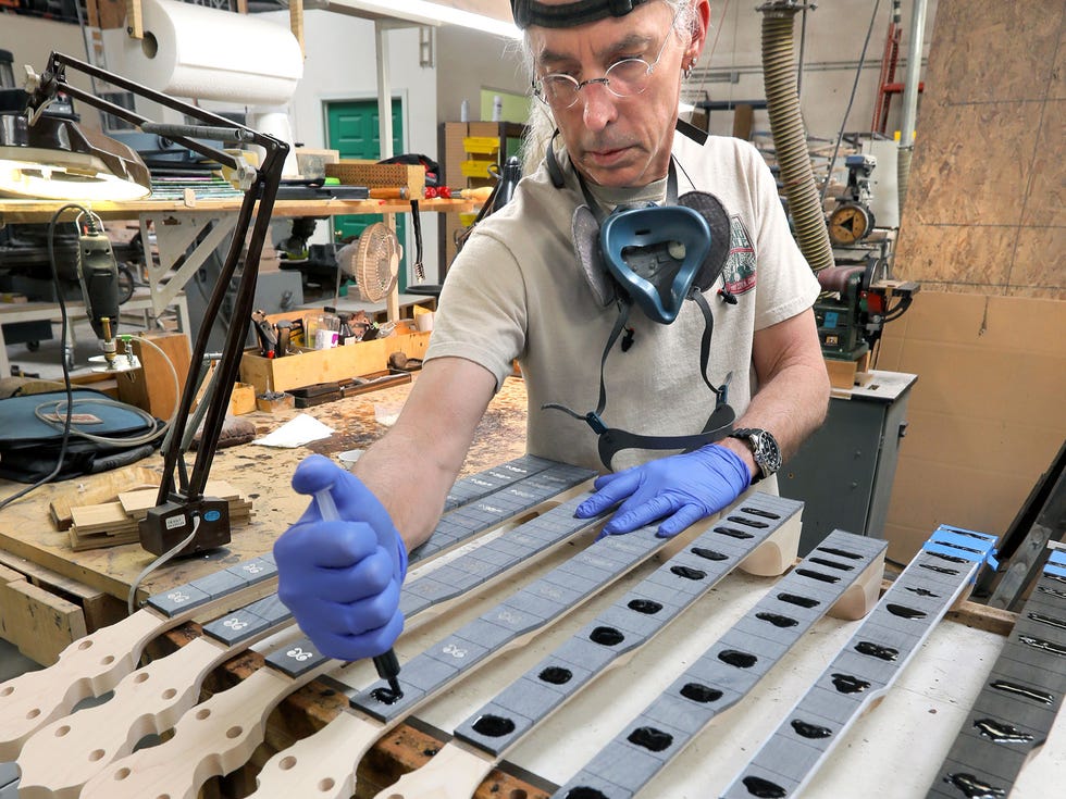 Marty Moore, a longtime employee of the Deering Banjo Company, applies epoxy resin for the intricate fret inlays for banjo fingerboards.