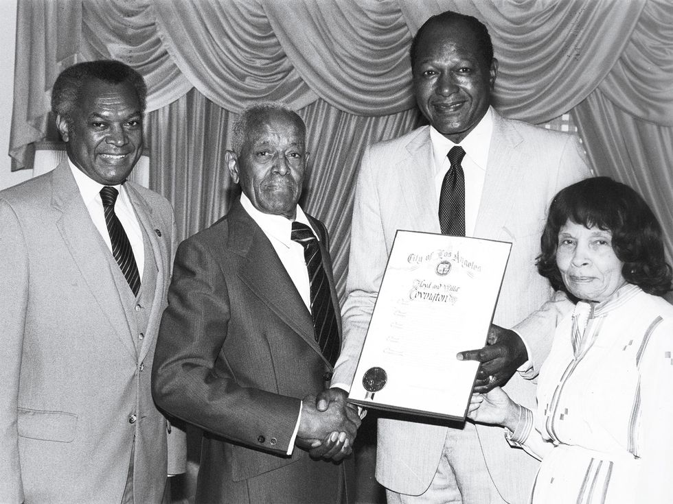 L.A. mayor Tom Bradley holds a certificate declaring April 24, 1984, as Floyd and Alma Covington Day; he’s joined by John Mack (far left), then president of the Los Angeles Urban League.