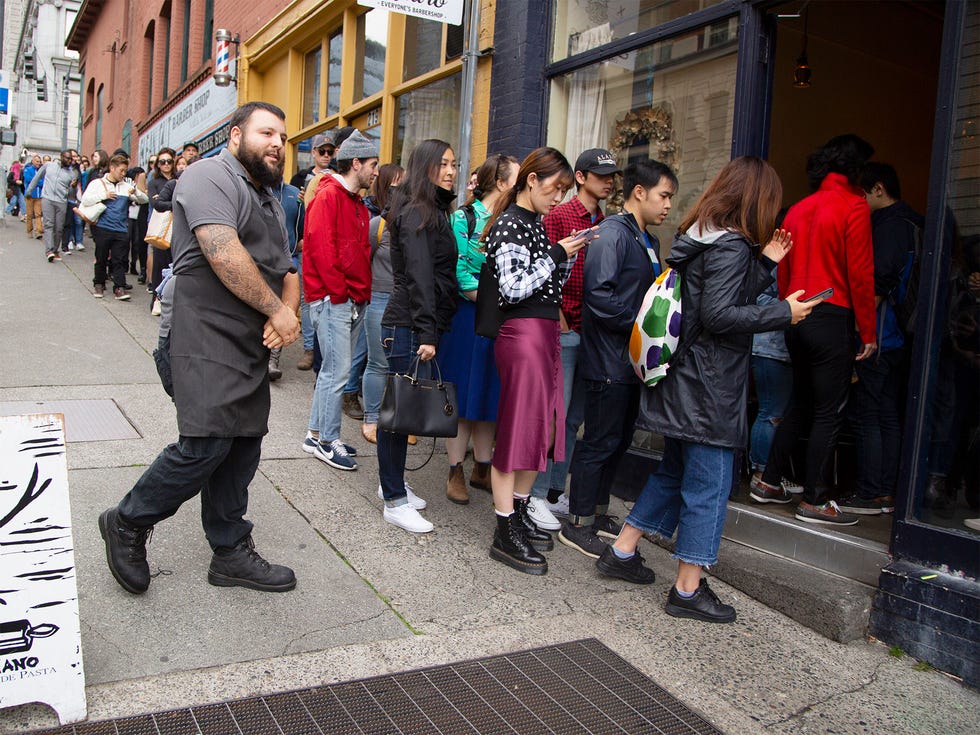 Eric Marrow (left) opens the door for a long line of customers at Il Corvo for the start of lunch service.