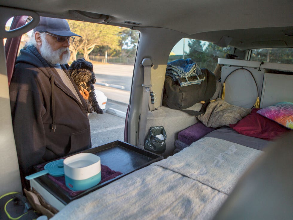 One Starfish guest Tom Mitropolis and his dog, Buster, stand outside their 1996 Chevy Suburban, where they sleep and eat.