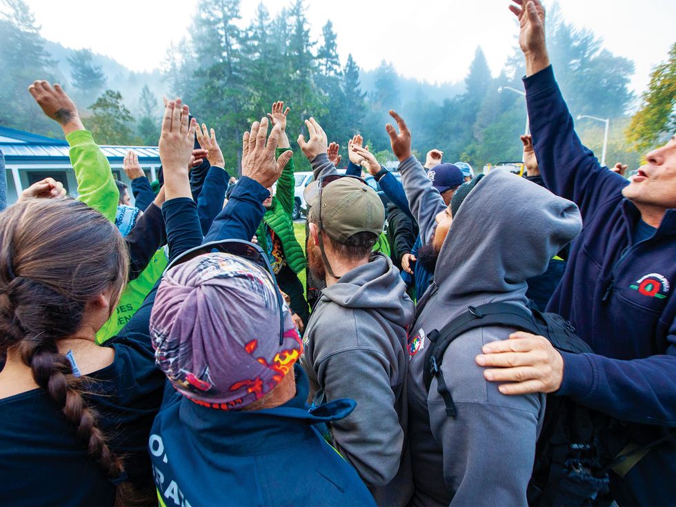 One of the teams participating in a TREX burn raise their hands in unity following an early morning meeting. Most of those who will set fires must pass a “pack test” by hiking three miles in 45 minutes while carrying 45 pounds.