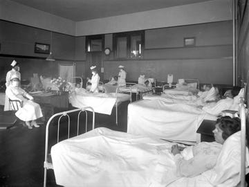 Nurses wearing breathing masks administer to patients in the ward, believed to be the isolation ward at Pasadena's Wilson High School during the 1919 influenza epidemic.