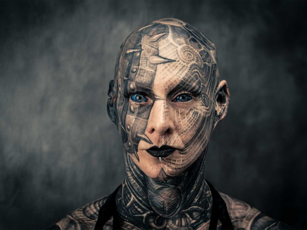 Kris Kai’s head and face feature work by Paul Booth. Her sclera tattoos are by Luna Cobra. Kai believes that her tattoos give her superhuman strength and that the more ink someone has, the more intelligent they become.