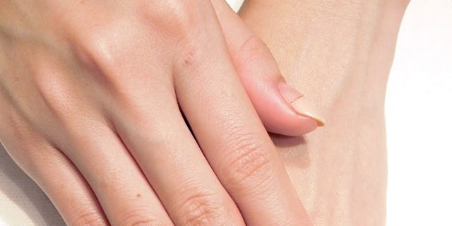 Finger, Skin, Nail, Jewellery, Logo, Nail care, Ring, Engagement ring, Metal, Beige, 