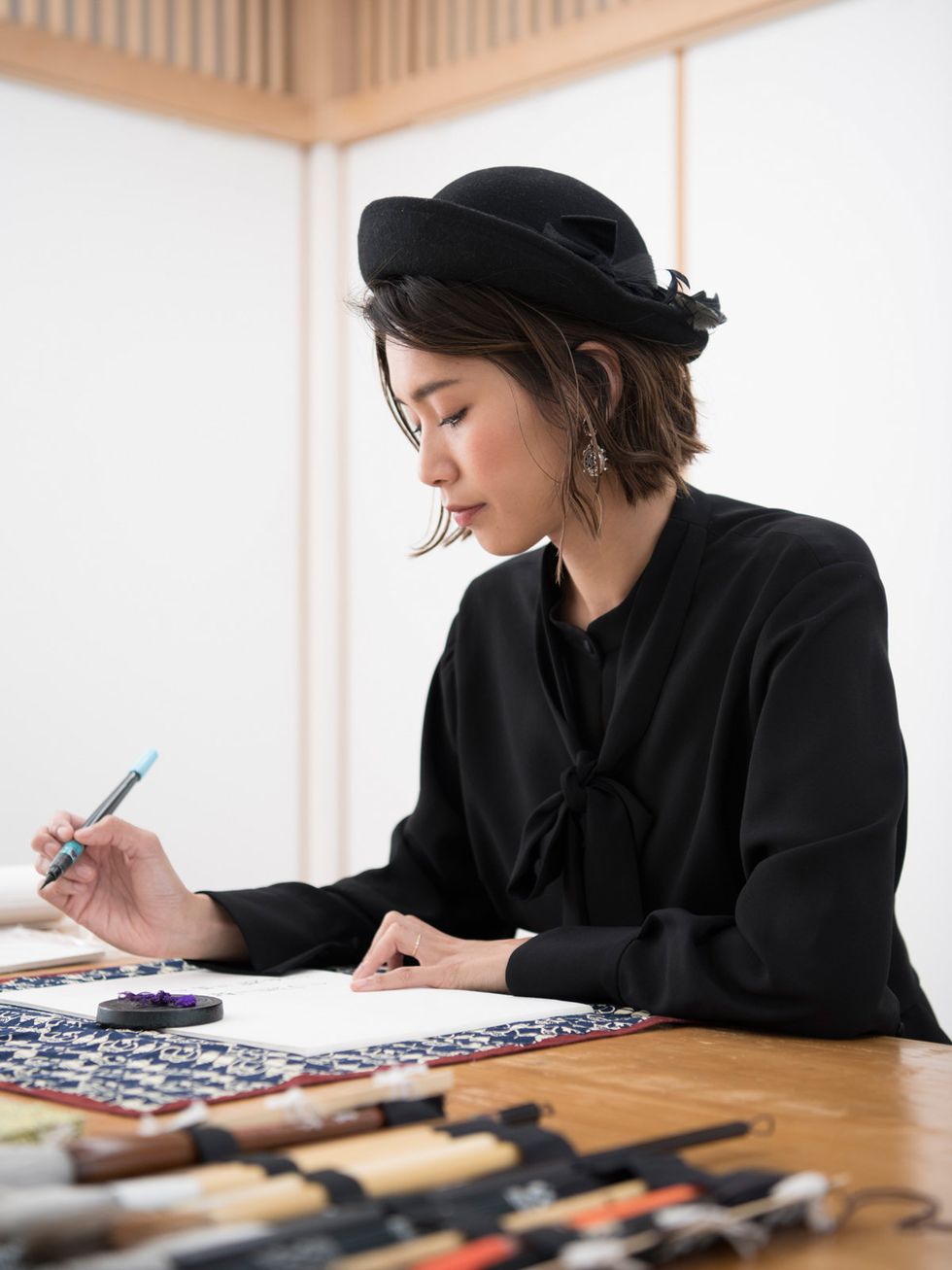 Hand, Hat, Writing implement, Table, Stationery, Fashion accessory, Headgear, Pen, Desk, Office supplies, 