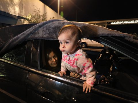 selena rivera, held by mom bertha, looks out the window before bertha and husband manuel cover it with the blanket above to spend the night here,  manual has to work in the morning at his security guard job, and the family sleeps in their car in the parking lot of jewish family service of san diego