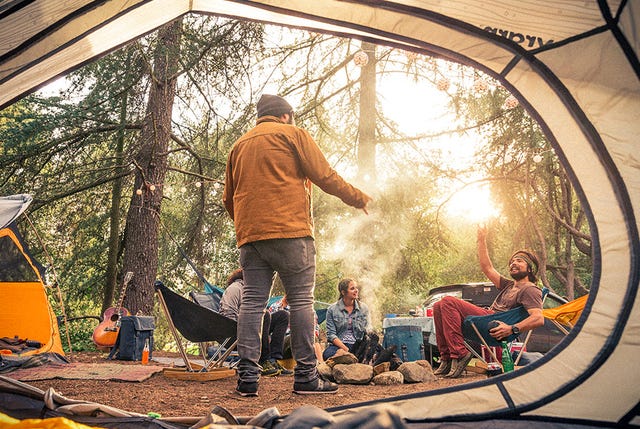 the view from inside a tent of a group of people sitting around a stone fire pit