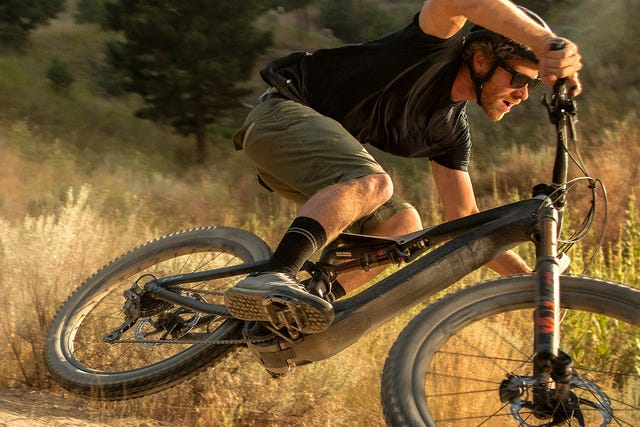 a man making a wide turn on a black electric mountain bike