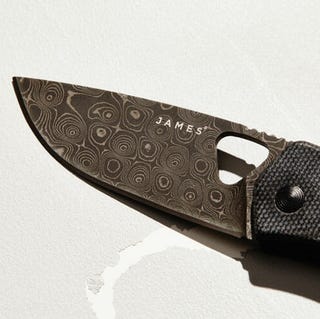 Damascus-Steel-Gear-Patrol-Lead-Featured a damascus steel pocket knife blade on a white background