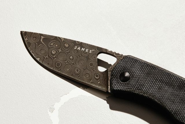 a damascus steel pocket knife blade on a white background