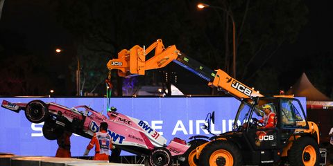 Course workers remove the Force India machine of Esteban Ocon in Singapore.
