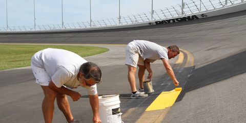 Workers put the finishing touches on the recent repave project in turn three at Daytona International Speedway.