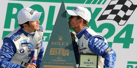 Scott Pruett, right, kisses his fifth Rolex 24 trophy. He's joined by teammate Memo Rojas.
