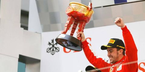 Fernando Alonso celebrates his victory in the Chinese Grand Prix as runner-up Kimi R&auml;ikk&ouml;nen looks on.