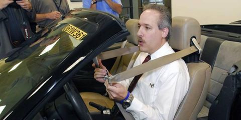 Ford's Stephen Rouhana, shown demonstrating four-point seat belts, says before the new belts can be installed in Ford vehicles, the automaker has to adapt the design for use by pregnant women, and federal standards must change. Four-point belts currently are illegal.