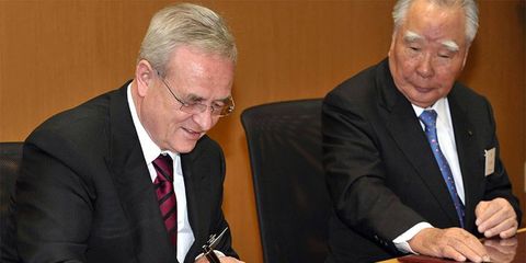 Volkswagen CEO Martin Winterkorn signs the agreement to buy nearly 20 percent of Suzuki. Osamu Suzuki (right), CEO of Suzuki, looks on.