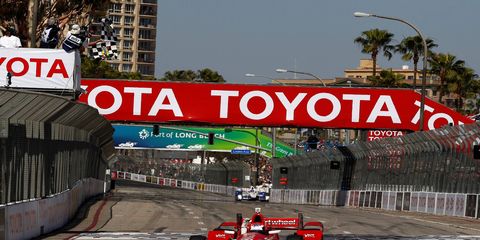 Scott Dixon crosses the finish line at Long Beach, with Helio Castroneves coming in to take second.