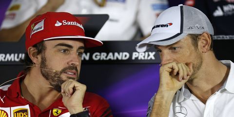 Fernando Alonso and Jenson Button talk to one another during Thursday's Formula One press conference.