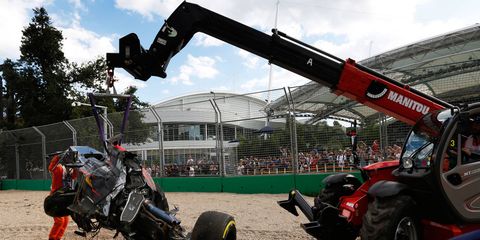 Fernando Alonso's Ferrari is removed from a gravel area in Australia.