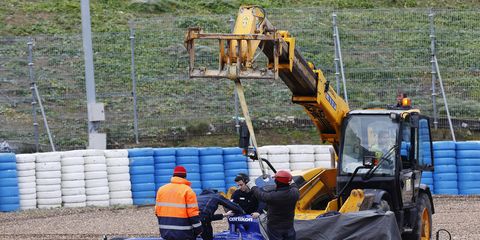 A crane removes a disabled car from the track at Jerez, Spain, during preseason testing. Cranes are used during races, as well.