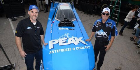 Bryan Emrich, chief marketing officer for Old World Industries, left, and John Force, right, show off Force's 2015 colors during a press conference in Las Vegas on Saturday.