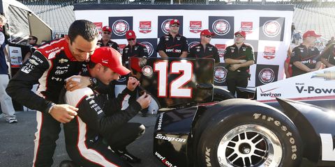Will Power attempts to affix his pole sticker to the back of his car while receiving a hug from Team Penske teammate Helio Castroneves. Power won the pole for Sunday's race in Sonoma.