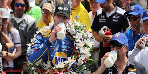 Alexander Rossi, left, and team owner Michael Andretti, right, take the traditional drink of milk in victory lane at Indianapolis Motor Speedway on Monday.