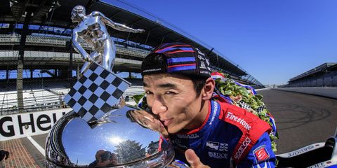 Takuma Sato celebrates his Indianapolis 500 victory by kissing the Borg-Warner Trophy on the yard of bricks.