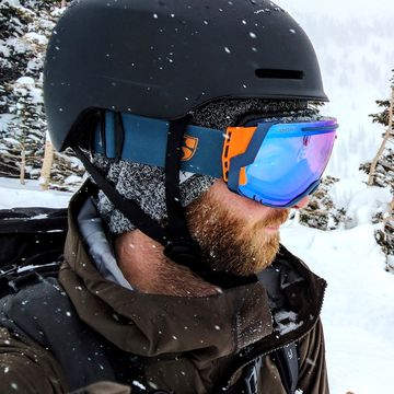 two skies looking downhill on slope wearing helmets and ski goggles