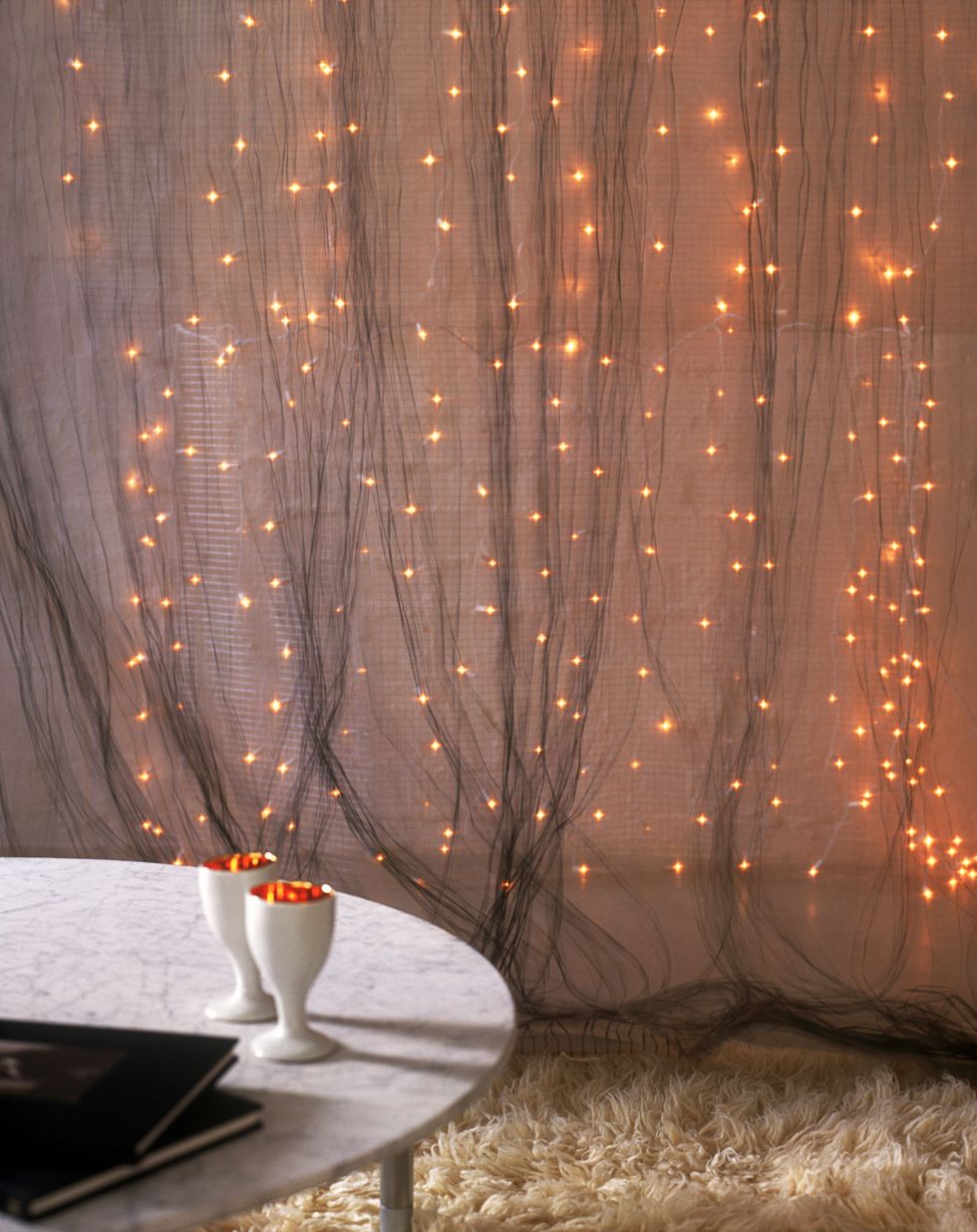 Unisci più fili di luci di Natale per creare una tenda di luce impalpabile, puoi sovrapporla alle tende della sala oppure crearne una nuova su una parete vuota della stanza