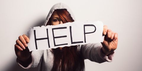Una donna tiene un mano un cartello con la scritta help, aiuto, perché le donne vittime di violenza devono chiedere aiuto