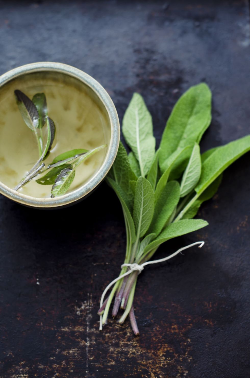 Sage tea in small cup with bunch of sage leaves