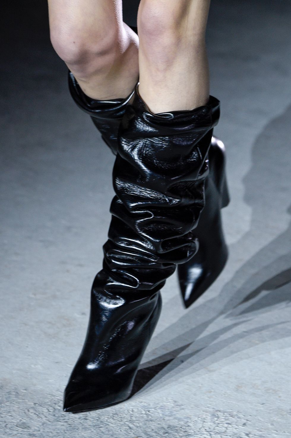 Modella alla sfilata Saint Laurent con dettaglio sugli stivali neri alla Parigi Fashion Week.